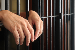 bigstock prisoner behind bars hand of p 353865248